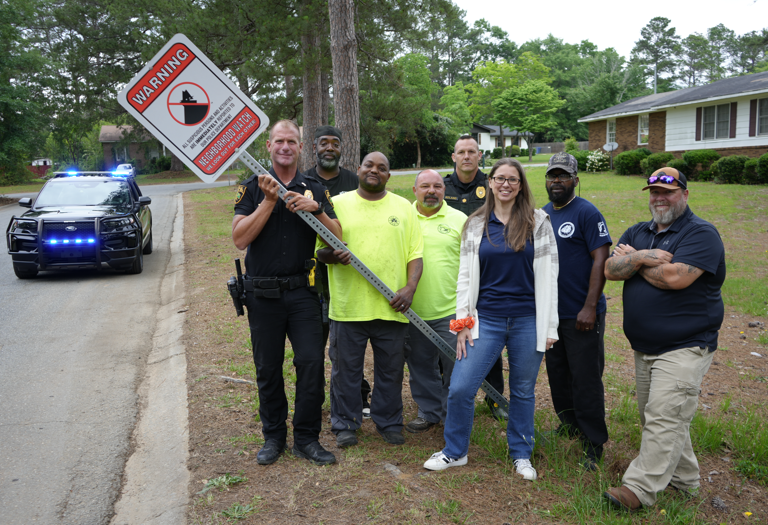 group of people with neighborhood watch sign